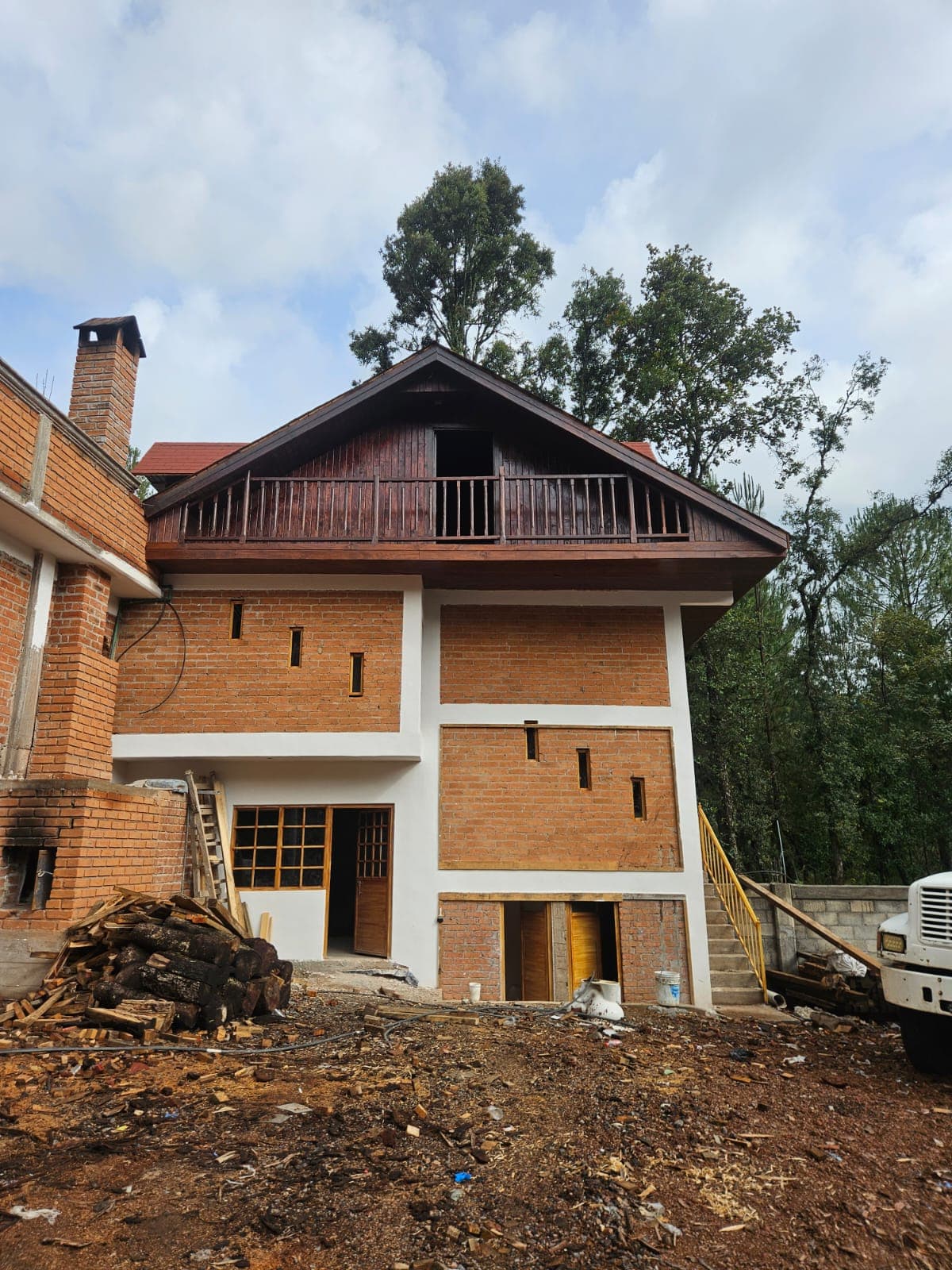 Vivienda de varios niveles construida en ladrillo y concreto con una cabaña de madera integrada en la parte superior.
